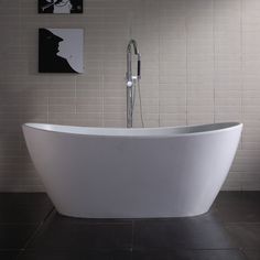 a white bathtub sitting next to a toilet in a bathroom with black tiles on the walls