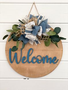 a welcome sign hanging on the side of a white building with blue and green decorations