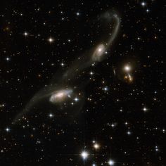 two spiral shaped objects in the middle of a dark sky filled with stars and small white dots