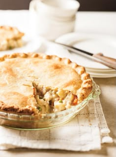 a pie sitting on top of a table next to a plate with a knife and fork