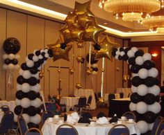 black and white balloons are hanging from the ceiling in this banquet room decorated for a party