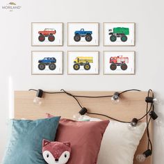 a bed with pillows and pictures on the wall above it that have trucks drawn on them