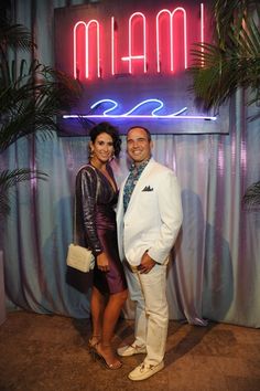 a man and woman standing in front of a marquee sign at an event