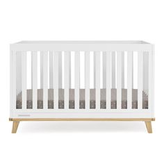 a white crib with wood legs and grey sheets on the bottom, against a white background