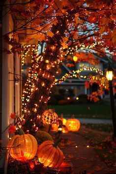 pumpkins are lit up in front of a house with lights on the trees and bushes