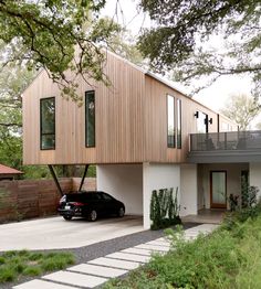 a car is parked in front of a house with wooden siding and two story windows