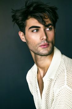 a young man with dark hair wearing a white shirt