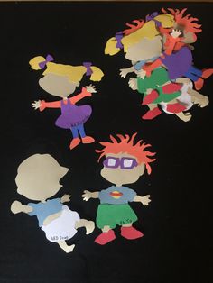 paper cut out of children's faces on a black surface with one child in the middle