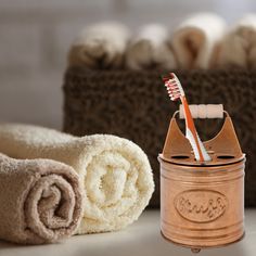 two toothbrushes are sitting in a jar next to some folded towels and a basket