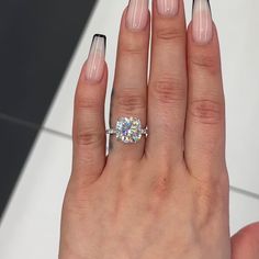 a woman's hand with a ring on top of it and a diamond in the middle