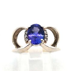 * Sophia Fiori 925 Sterling Silver Oval Tanzanite Diamond Accents Split Shank Ring * Ring size: * Band width: 2.3 mm  * Top of ring measures: 3/8" x 3/8" * Height: 3/16" * Weight: 3.9 tgw  * 1 Oval Tanzanite measures approximately 8.7 mm x 6.8 mm  * 6 Round Diamonds measure approximately 1.2 mm each * Ring can be resized for an additional fee.  * Unmarked. * Professionally assayed. * Condition: As pictured. * S5975    Exported By ExportYourStore :) Hallmarked Oval Tanzanite Jewelry, Oval Tanzanite Rings Fine Jewelry, Oval Tanzanite Ring In White Gold, Split Shank Ring, Tanzanite Diamond, Split Shank, Round Diamonds, Jewelry Rings, Ring Size