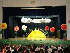 the stage is decorated with paper flowers and sun