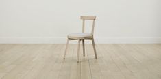 a chair sitting on top of a hard wood floor next to a white painted wall