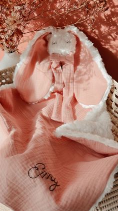 a pink blanket with the word happy written on it next to a small tree and wicker basket