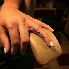 a woman's hand with a small tattoo on her left thumb and the word love written in cursive font