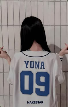 a woman with black hair standing in front of a tiled wall