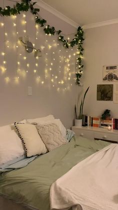 there is a bed with pillows and lights hanging from the wall above it in this bedroom