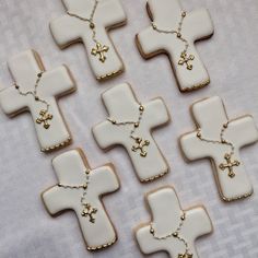 several decorated cookies are arranged in the shape of crosses on a white tablecloth with gold trimmings