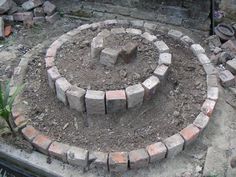 a circular brick fire pit in the middle of some dirt and bricks on top of it