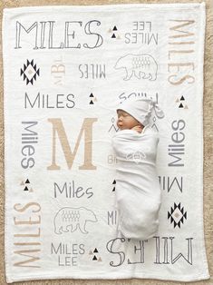 a baby wrapped up in a blanket with the letter m on it's side