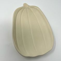 a white ceramic pumpkin shaped dish on a white surface with the top half turned to look like it has been cut in half