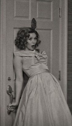 a woman in a dress is leaning against a door