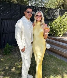 a man and woman in formal wear standing next to each other on the grass outside