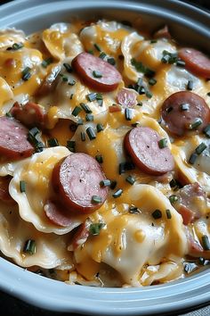 a bowl filled with pasta and sausages covered in cheese on top of a table