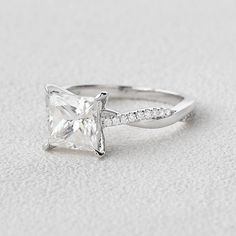 a white gold ring with a princess cut diamond and pave set diamonds on the band