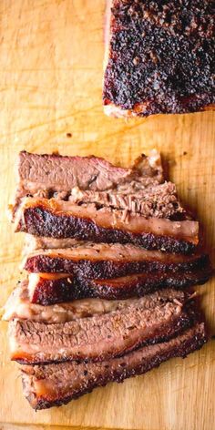 sliced meat sitting on top of a wooden cutting board next to another piece of meat