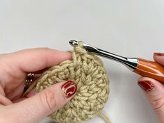 a woman is crocheting the end of a piece of yarn with a crochet hook