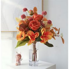 a vase filled with orange flowers next to a small figurine