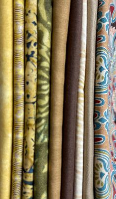 many different colored fabrics hanging on a wall