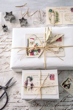 two wrapped presents tied with twine on top of a table next to scissors and other items