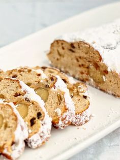 a white plate topped with slices of cake covered in powdered sugar and apple slices