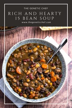 a bowl filled with beans and carrots on top of a wooden table next to bread