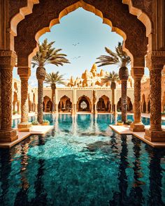 an outdoor swimming pool surrounded by palm trees and archways with water running through it