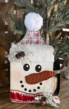 a snowman made out of a bottle on top of a wooden table next to a christmas tree