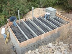 two men are working on the foundation of a house that is being built with cinder blocks