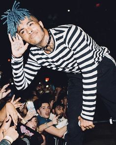 a man with dreadlocks on his head standing in front of a crowd at a concert