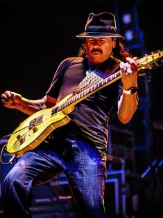 a man in a fedora playing an electric guitar