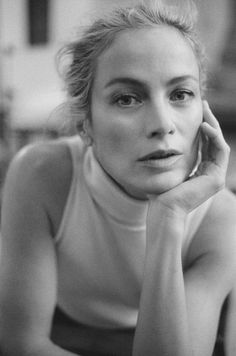 a black and white photo of a woman with her hand on her chin looking at the camera