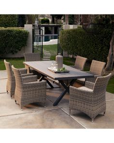 an image of a table and chairs in the middle of a patio with bushes behind it