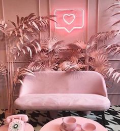 a pink couch sitting next to a table with two cups and saucers on it