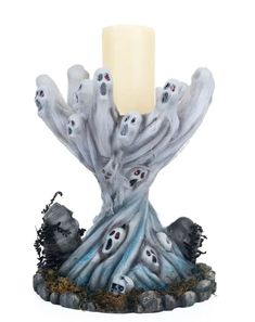 a candle that is sitting on top of a tree stump with ghost hands around it