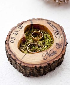 two wedding rings are placed in a ring holder made out of tree slices and moss