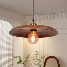 a wooden light fixture hanging from a ceiling in a room with white walls and windows