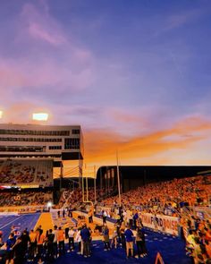 a crowd of people standing on top of a field at a football game under a cloudy sky