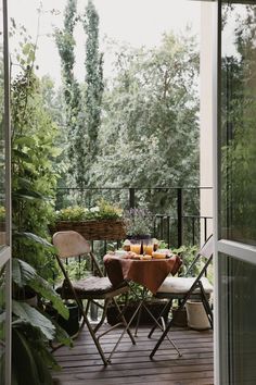 a table and chairs on a porch with trees in the backgroung area