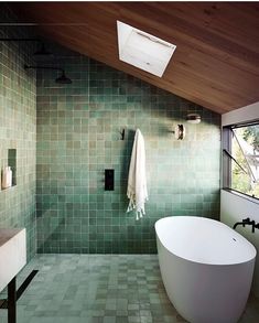 a bath tub sitting under a bathroom window next to a sink and shower faucet